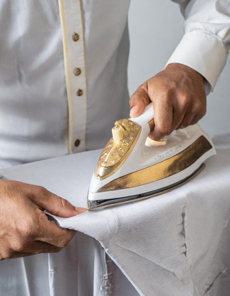 Firefly primer plano de manos planchando camisa artesanal o guayabera fondo minimalista blanco deta 796x1024 1
